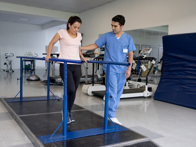 A physical therapist helps a patient practice walking